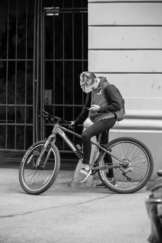 black and white pograph of person on bicycle by building