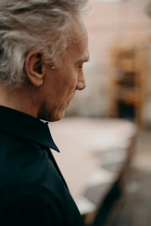 an old man wearing black collared shirt and dark black jacket