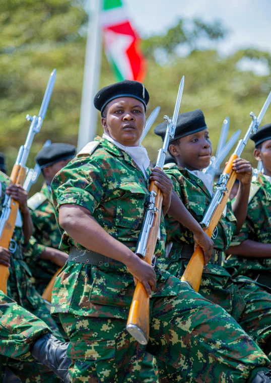 people with weapons, uniforms and hats stand in a parade