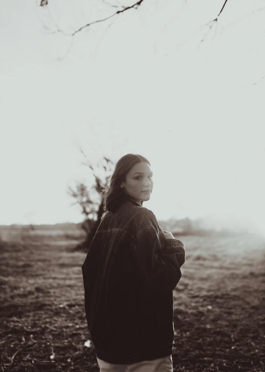 a woman standing alone near a tree nch