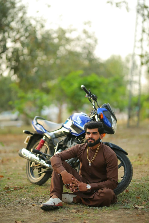 a man sitting next to his motorcycle outside