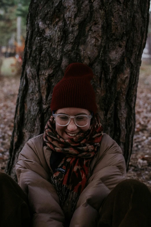 a woman wearing a scarf and glasses is sitting in the shade