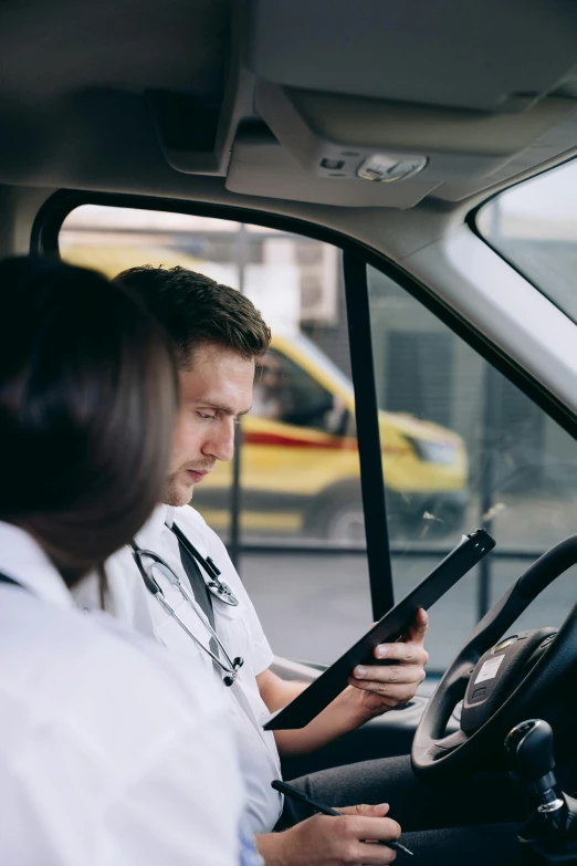 two people in white shirts are sitting at the wheel of a car