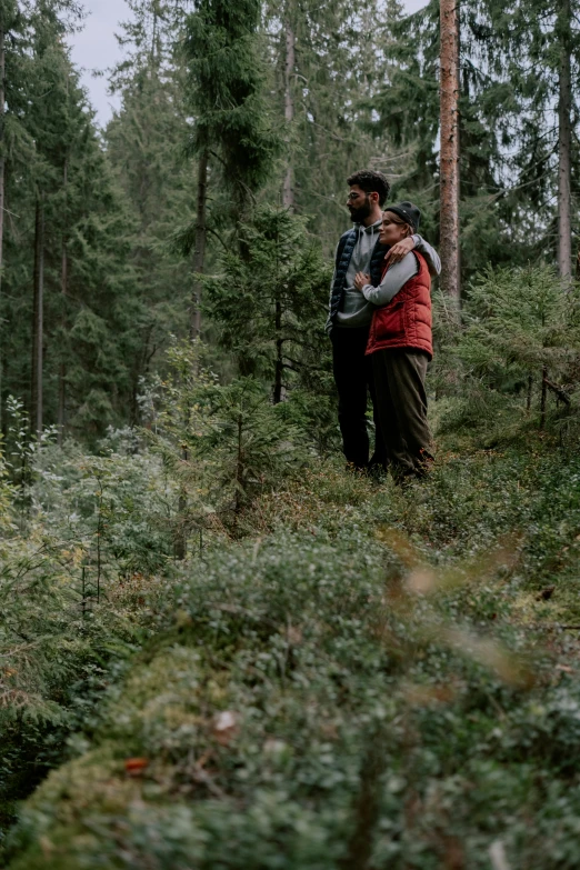 couple emcing in woods, surrounded by trees