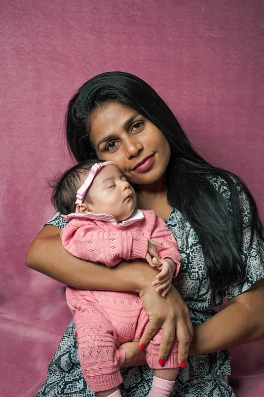 a woman holding a baby against a purple background