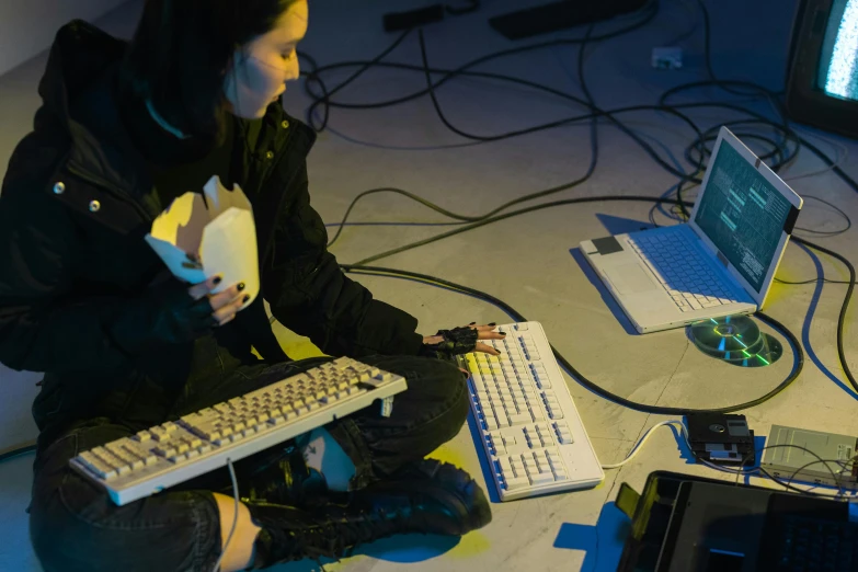 two people sitting in front of a keyboard on the ground