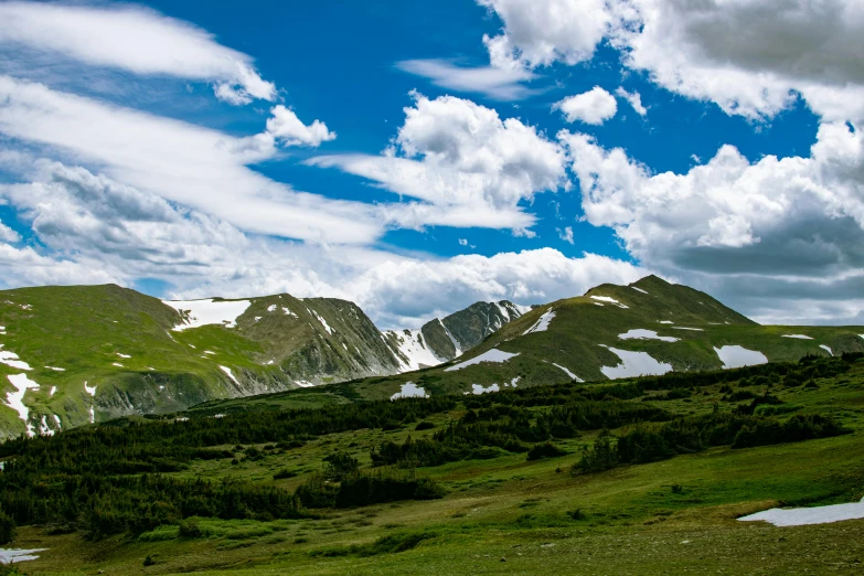 a large hill with snow on it's summits in the middle of the wilderness