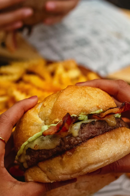 two hands holding up a burger on a bun