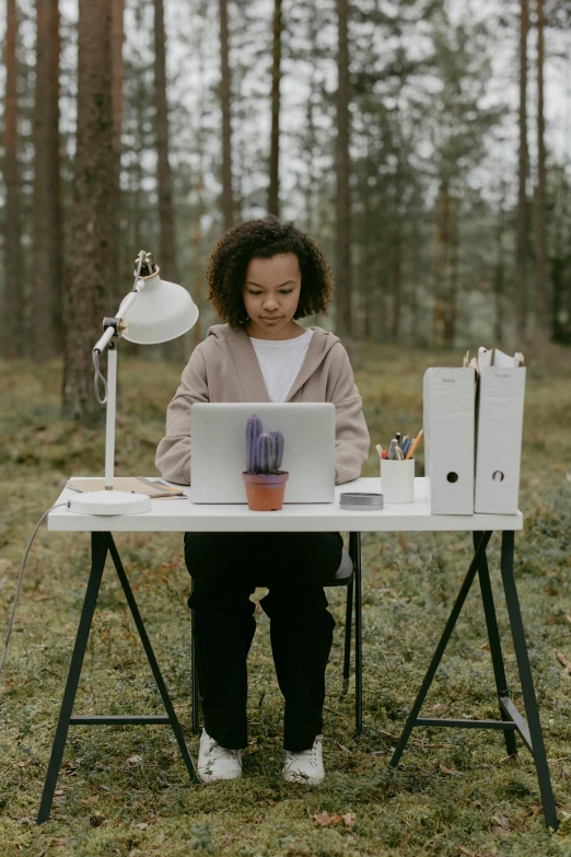 a woman sitting at a desk with a laptop in front of her on the ground