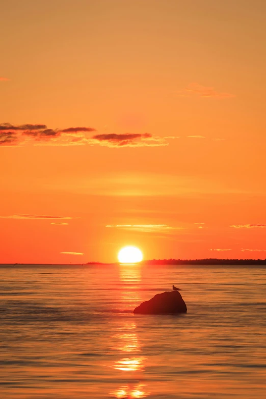 a sunset over the ocean with two surfers