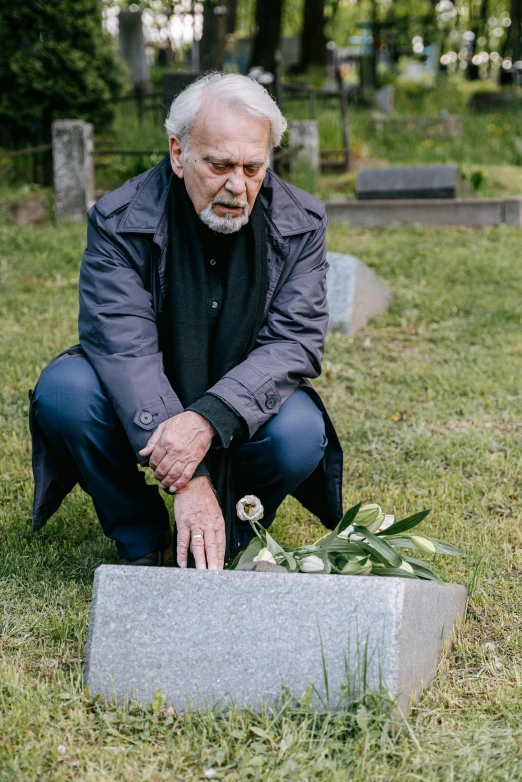 a man kneeling down in front of a gravestone