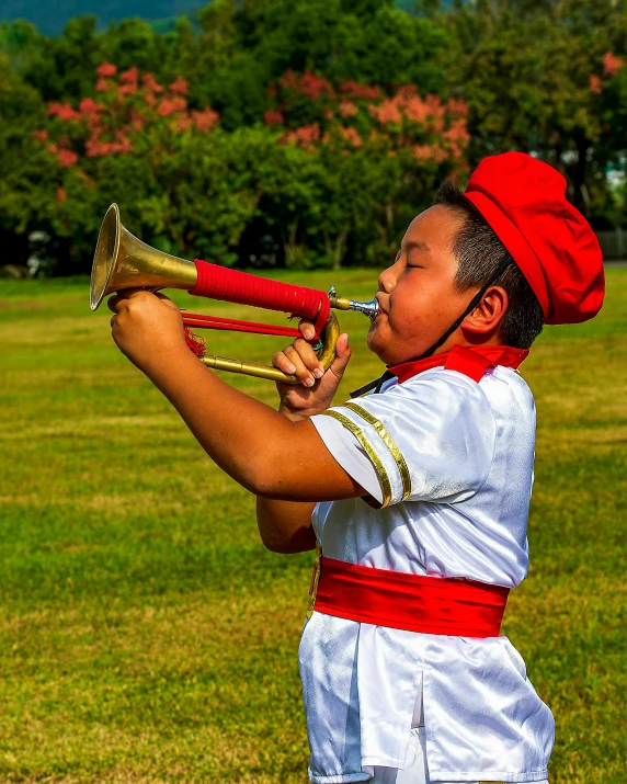 a boy playing a trumpet in the park