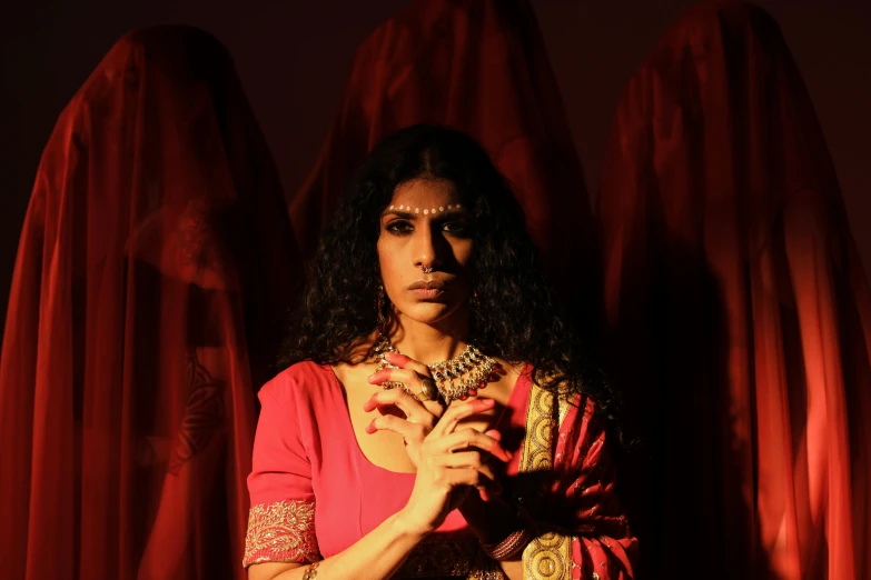 an oriental woman with dark hair posing in front of red curtains