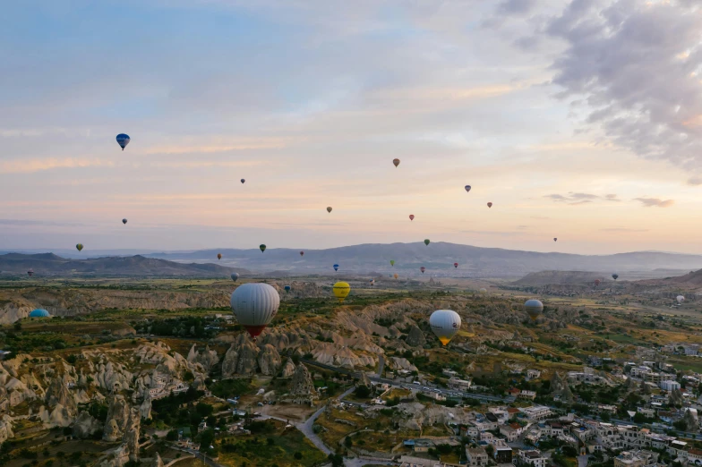  air balloons flying over a city and mountains