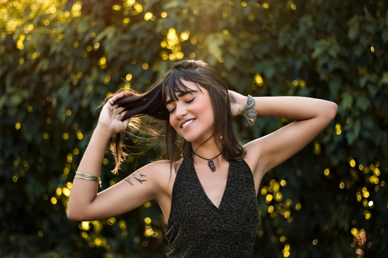 a woman wearing a black dress stands with her hair in the wind