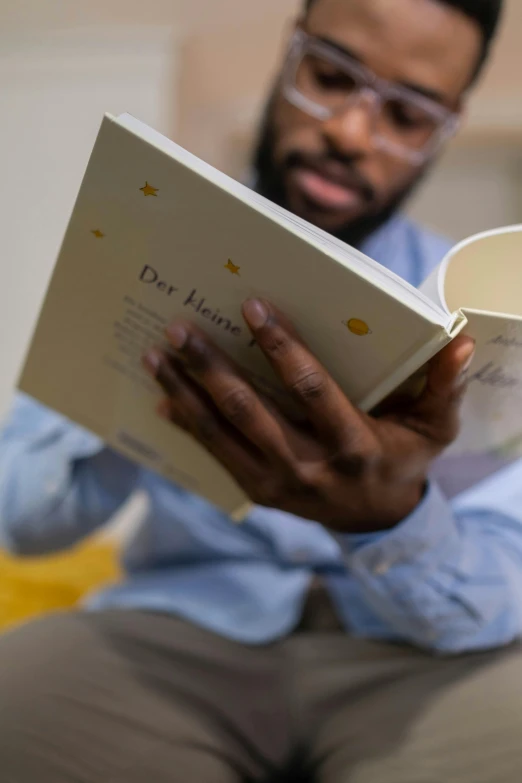 a man sitting on a couch reading a book