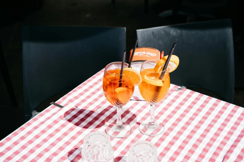 glasses with drinks sitting on a checkered red and white tablecloth