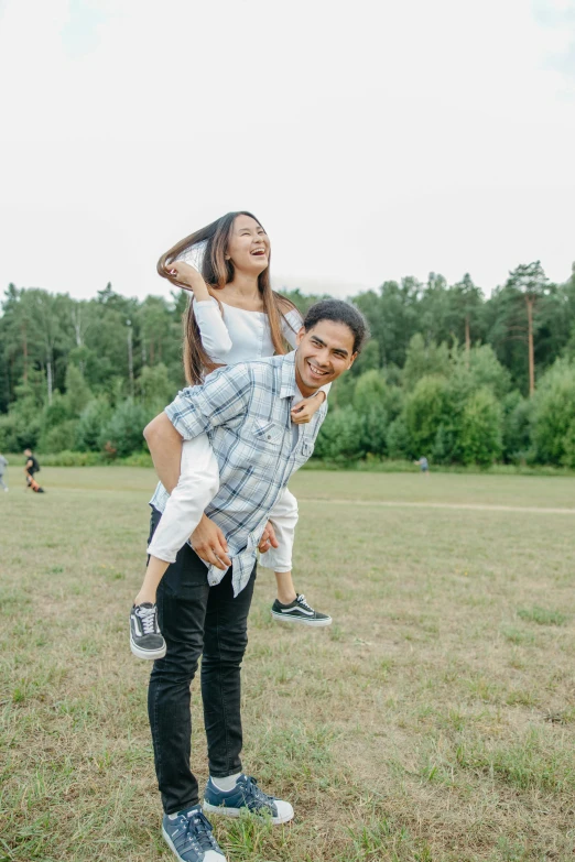 two young adults play on the grass together