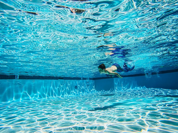 the woman swims underwater in the swimming pool