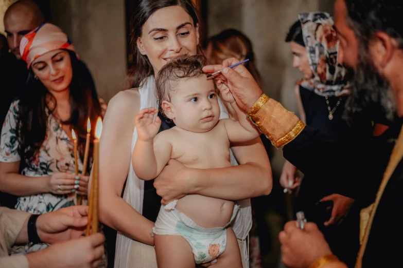 a little girl wearing diapers holding a candles in her arms