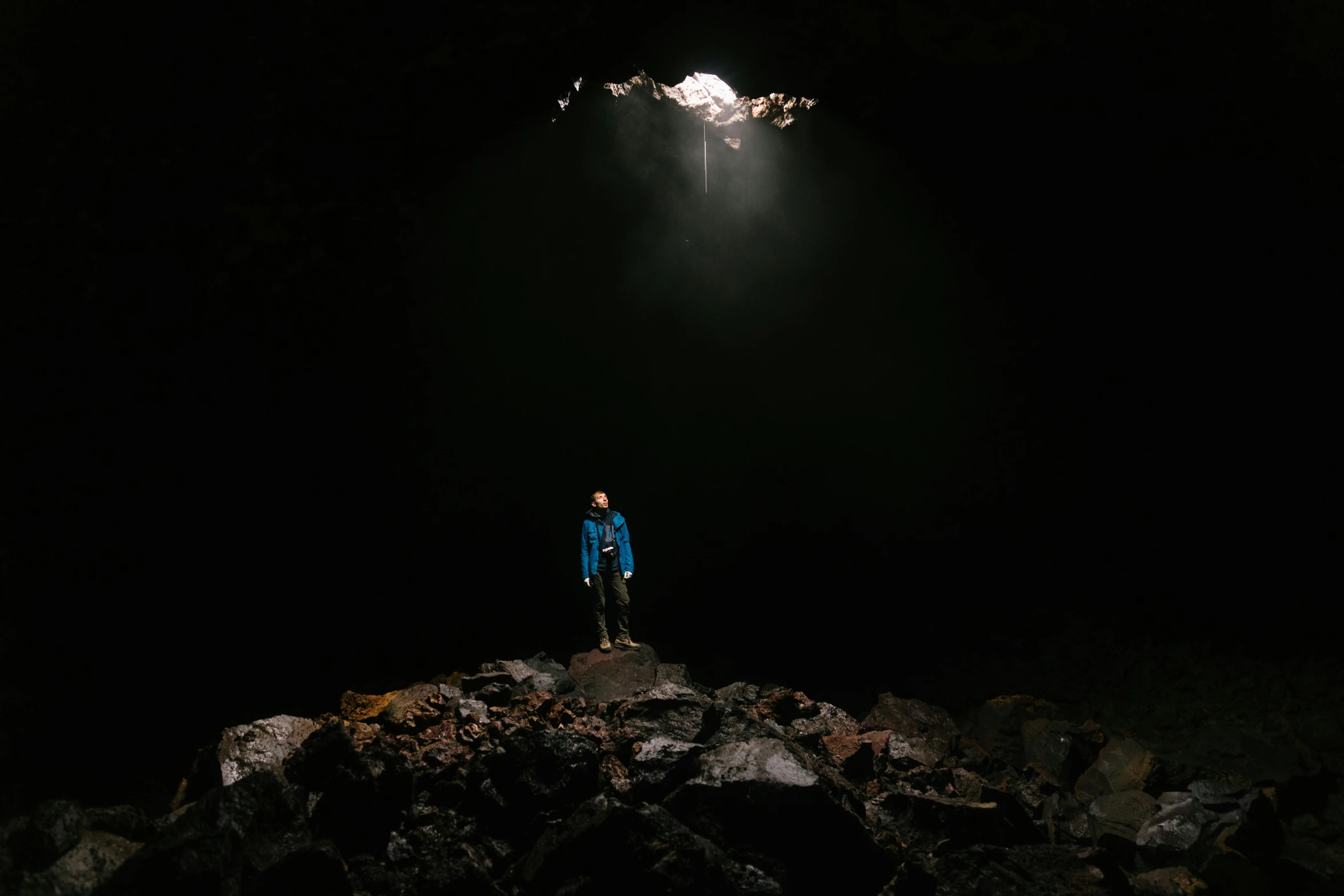 a person standing on rocks under light in dark