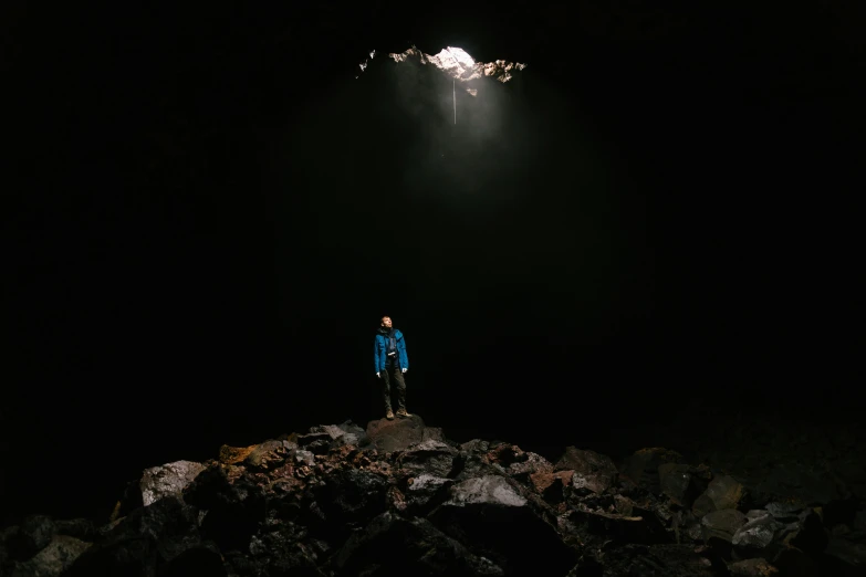 a person standing on rocks under light in dark