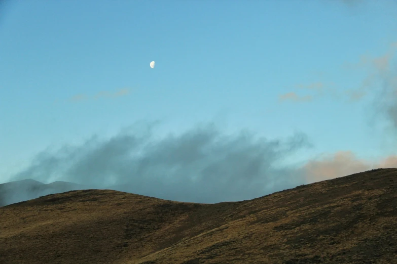 clouds float above the hills and a crescent