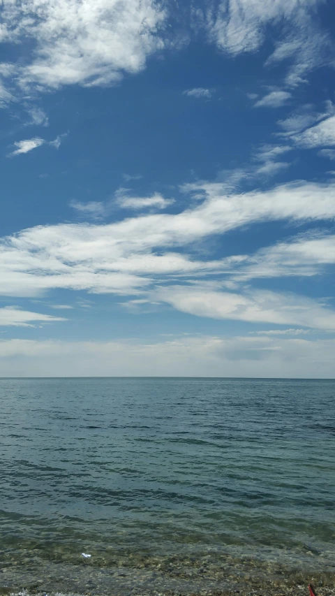 water and clouds near shore with boat on horizon