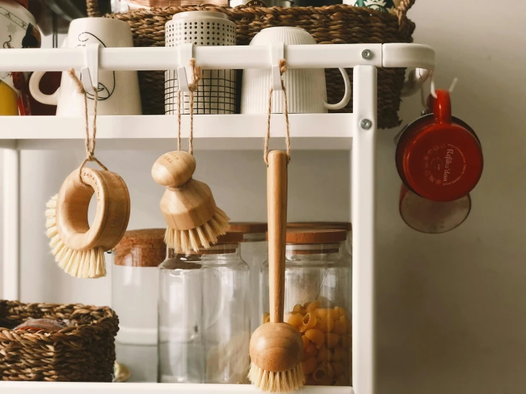 a shelf with jars and brushes, and a broom