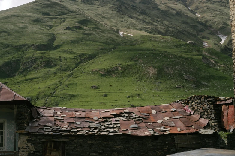 the roof of an old building in front of green mountain