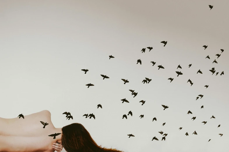 a woman is kissing her face in front of a flock of birds