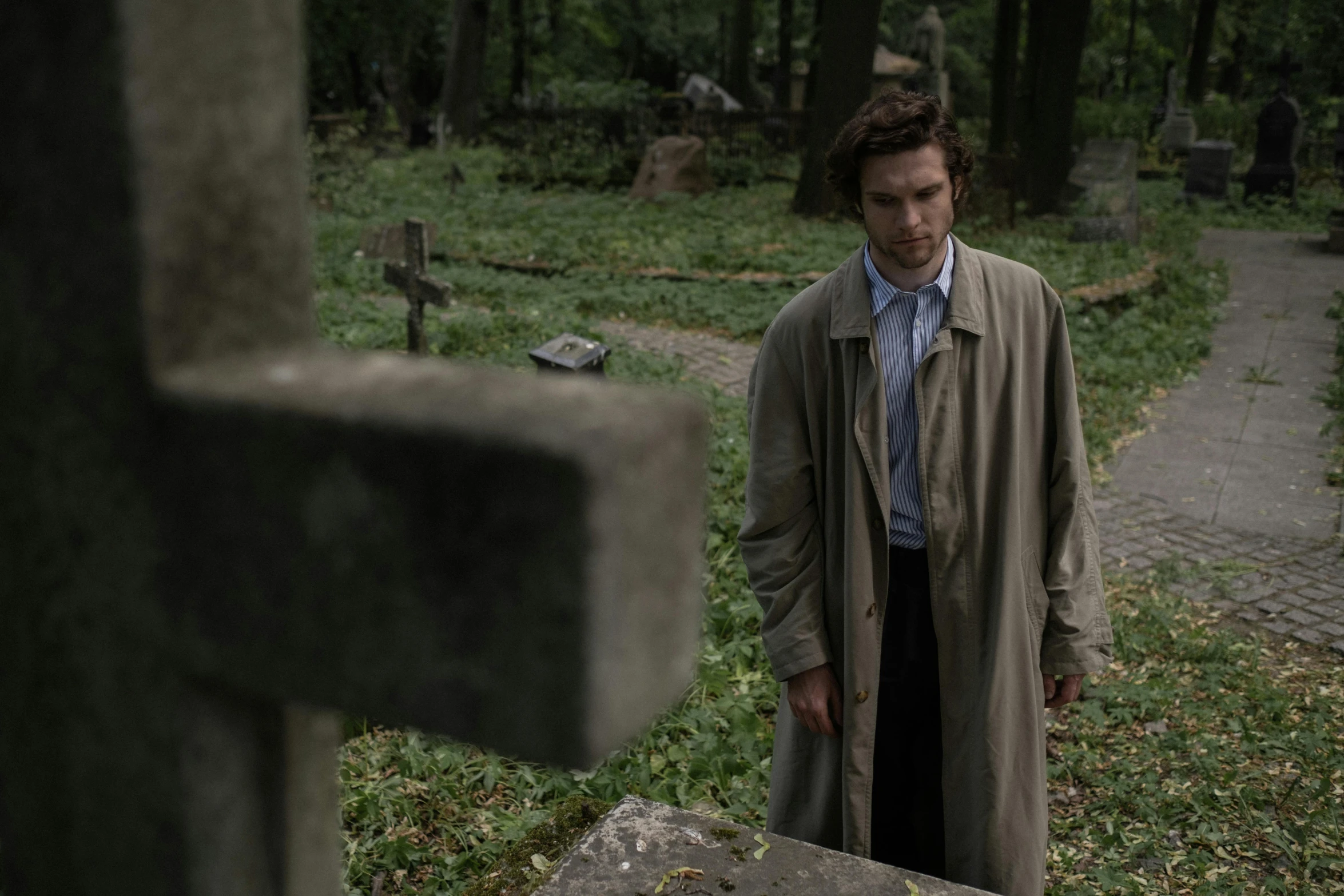 a man is walking near a grave in the grass