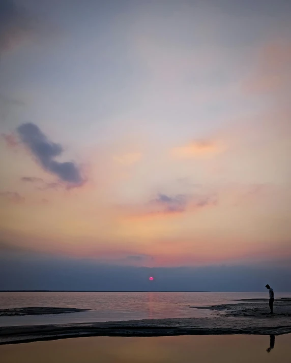 the person standing on the beach is holding their surfboard