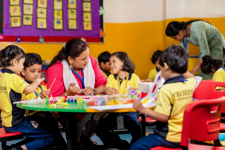 children sitting at tables with teachers working on soing