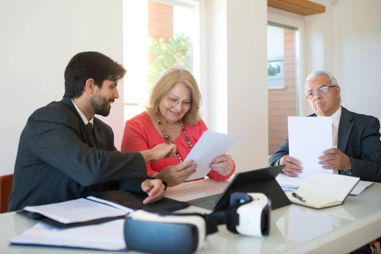 three people sitting at a table looking at a piece of paper