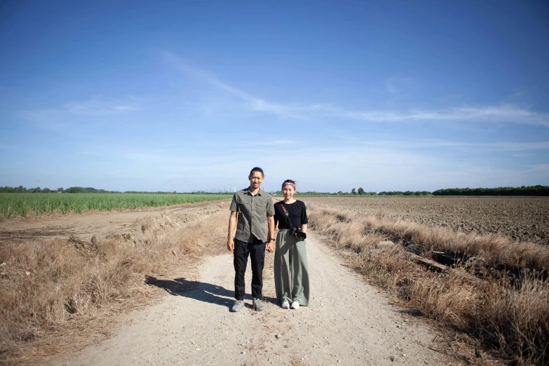 a man and woman standing in the middle of a dirt road