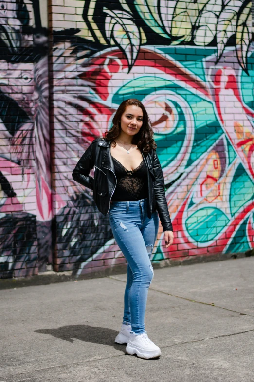 a woman standing in front of a graffiti wall