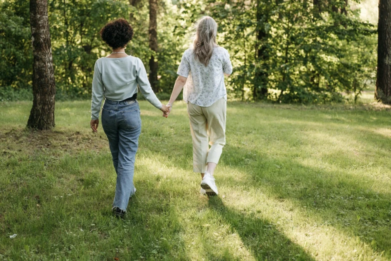 two women walking along the grass holding hands