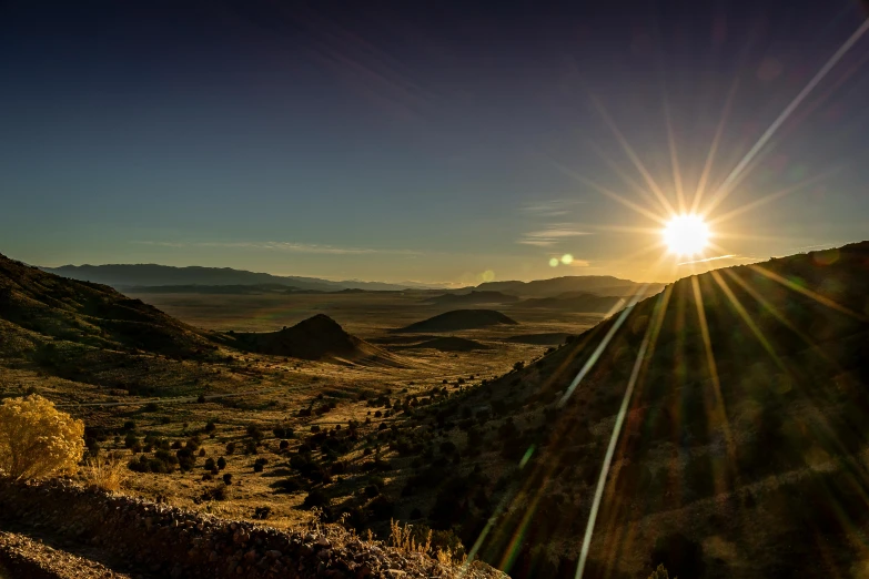 the sun shining in the distance over mountains