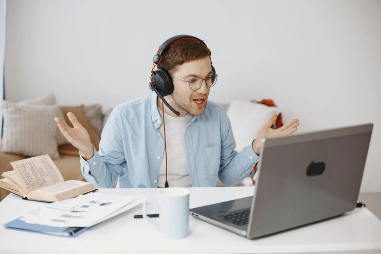 man sitting at table in front of laptop with headphones on