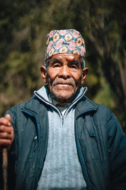 an older man with a colorful headdress holding a stick