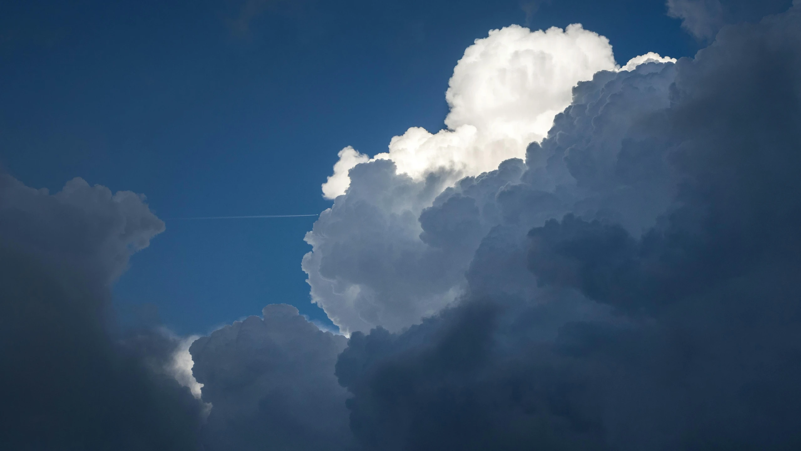 a large cloud with an airplane going over it