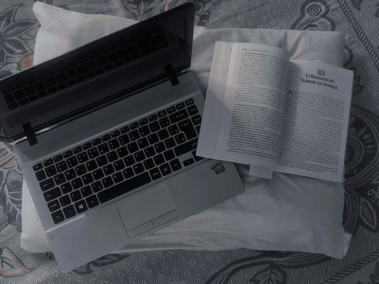 a laptop and a book laying on top of a bed