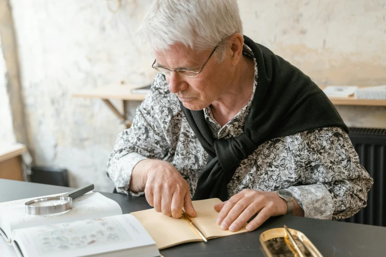 an elderly woman writing in a book at a table