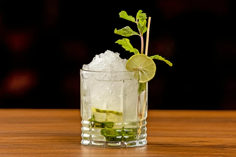 a cocktail with limes and ice sitting on a wooden table