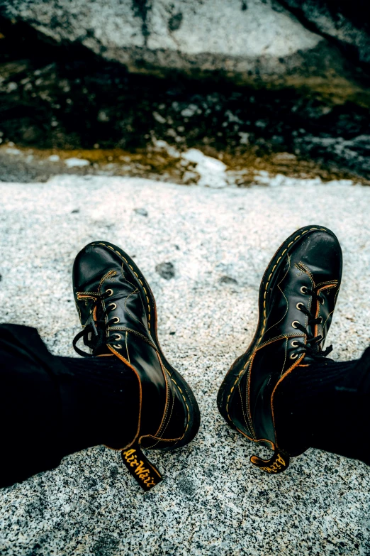 a man wearing a pair of black leather shoes on top of a stone walkway