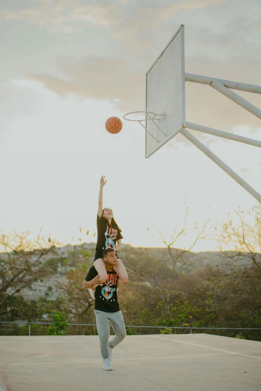 two people trying to reach for a basketball at a court