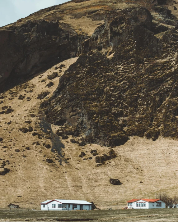 two small white houses in front of a rocky mountain