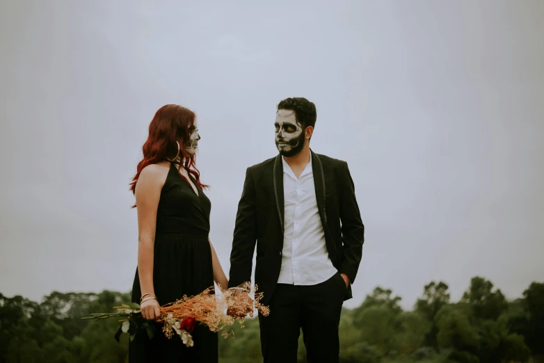 a man and woman dressed up as zombies walking hand in hand