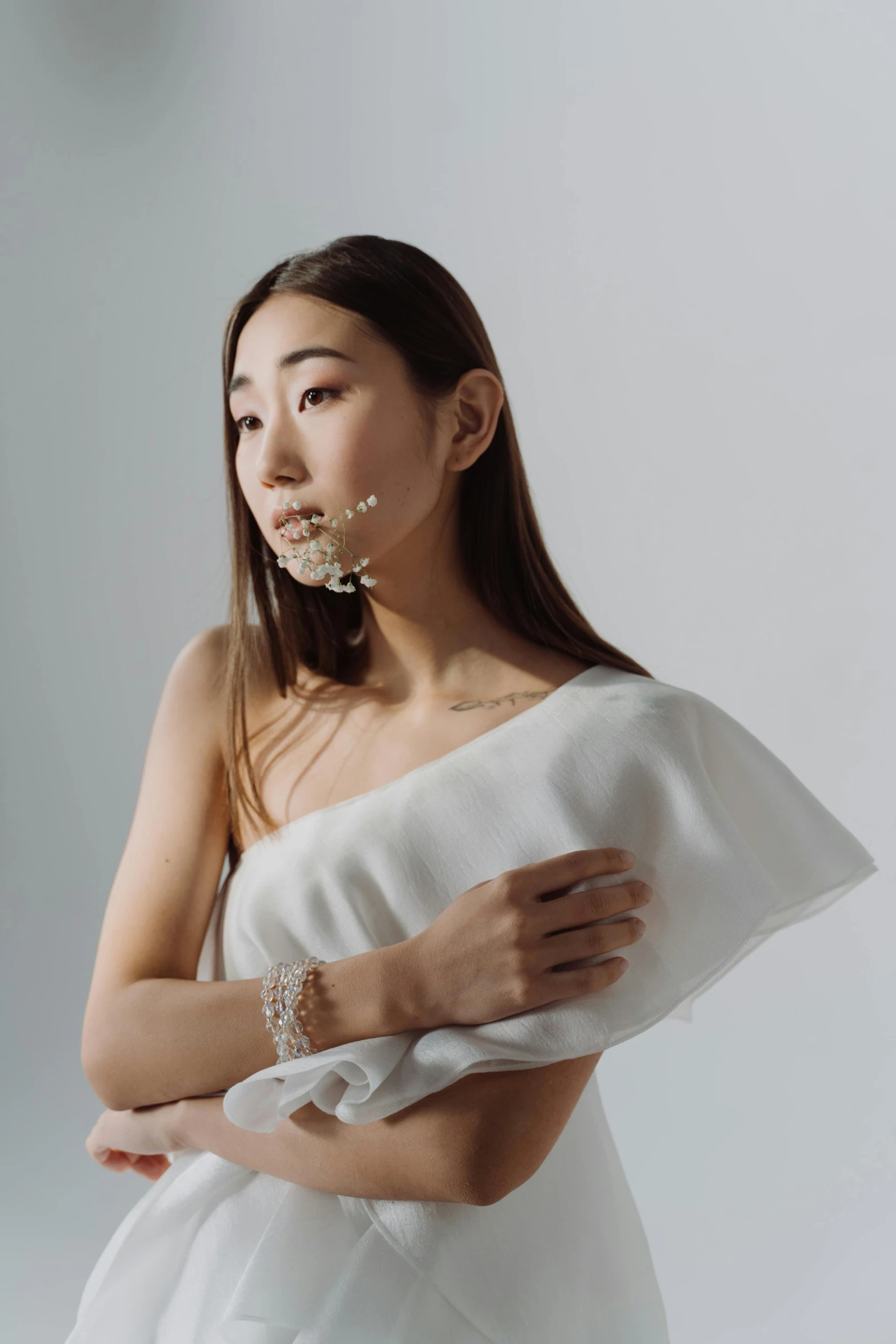 an attractive woman in white with gold jewels and rings on her neck